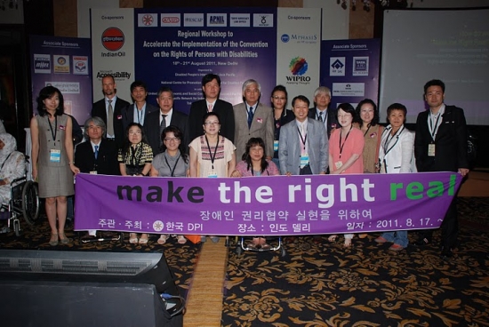 Group photo after the workshop with the  Korean Federation of the Disabled (KOFOD), holding a large sign with the slogan "make the right real"