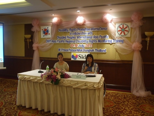 Ms. Saowalak Thongkuay sits at a table with Chona Sabo and speaks into a microphone. 