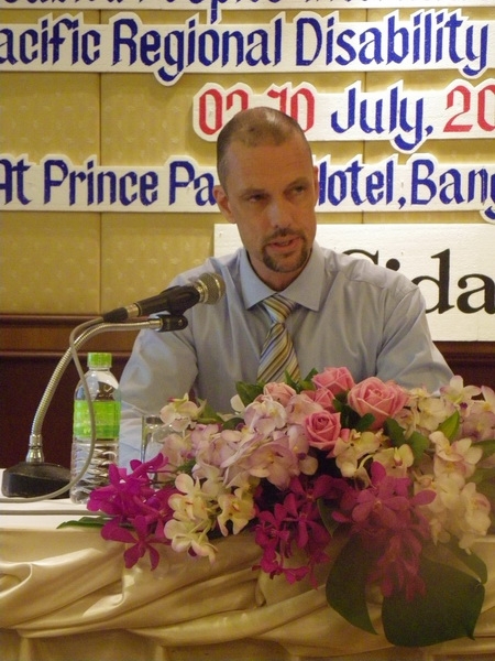 Mr. Patrik Andersson sits at a table and speaks into a microphone. 