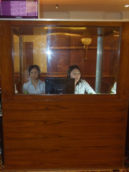 Two women sit in an enclosed booth with headphones on their heads. 