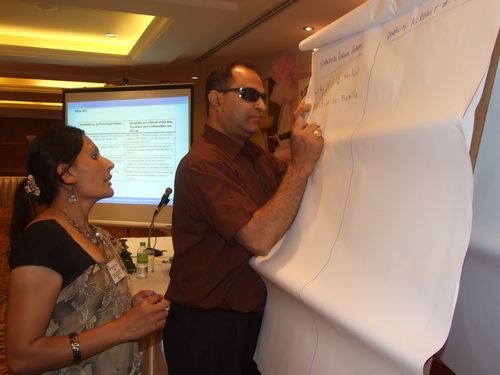 Birendra Raj Pokharel of Nepal writes his group's ideas on a flip chart during the training, while Ram Pyari Karki stands behind him. 