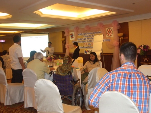 Mr. Soy and Ms. Channtey stand at the front of the room and present to seated participants in the foreground.