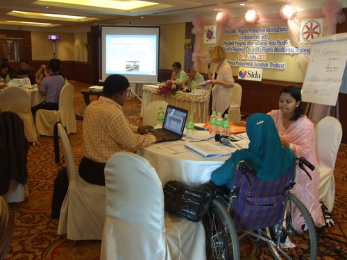 Roosevelt, MD Rasel, Ashrafun and Farhana sit at a table and work with training materials.