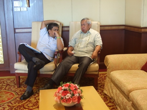 Lauro Purcil and Rannil Sorongon recline in comfortable chairs and talk. 