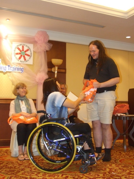 Saowalak Thongkuay gives Nathan Bond an orange bag while other facilitators look on.