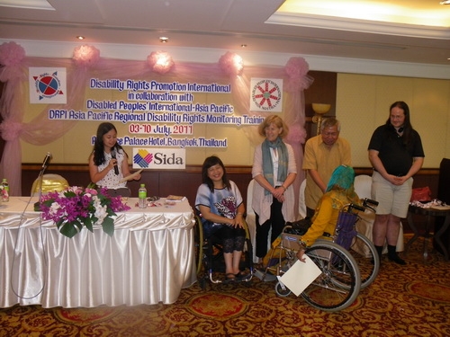 Ashrafun Nahar Misti of Bangladesh holds her certificate in front of facilitators. Lauro shakes her hand in congratulations.