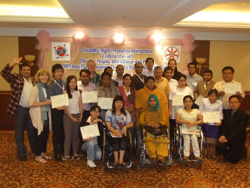 Participants, interpreters & facilitators pose together with their certificates and smile. 