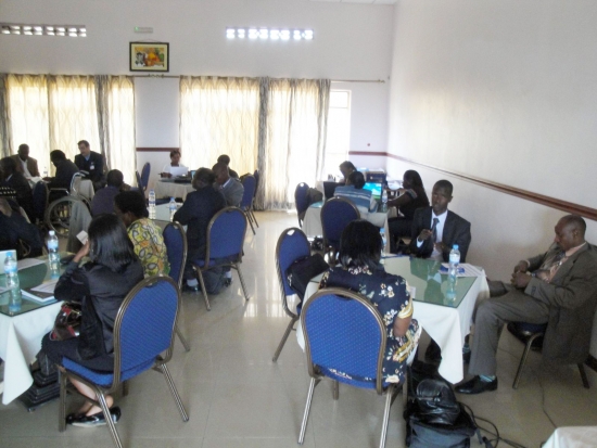 Participants sit in groups at small circular tables in a room with white walls.