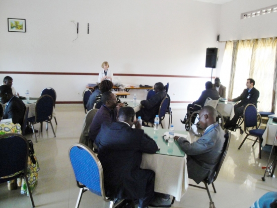 All participants are reading their materials, while Marcia Rioux speaks into a microphone.
