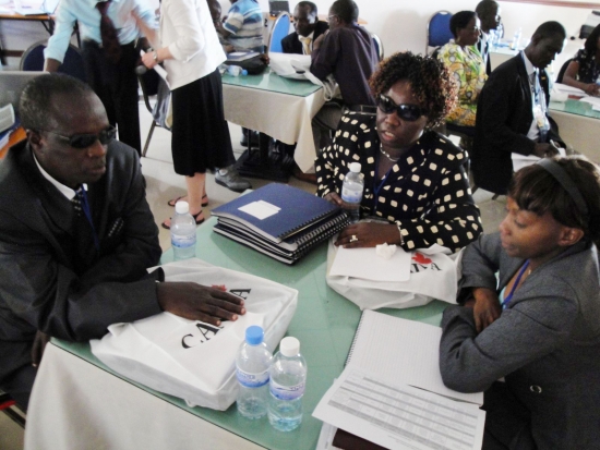 <p>
	A man and two women sit around a circular table with training materials in front of them.</p>
