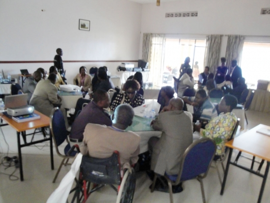 Participants sit separately at three large tables in the training room.