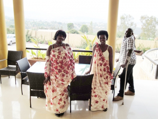 Mrs. Saphira Nyiransengimana and Apoche pose on a veranda at the centre of the photo, while Bruno Shyirambere looks on. 