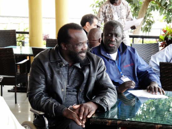 Tambo Camara and Mohamed Fall sit beside each other at a table on a veranda.