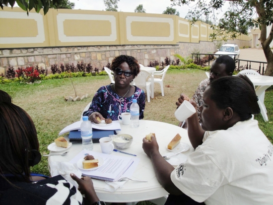 Roseweter Mudarikwa and Esther Kyozira and a couple of others sit outdoors at a round table and have a snack.