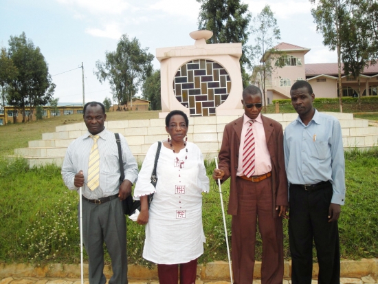 Kennedy Oriko, Amon Anastaz, Magdalina T. Kaihuzi and Felician Mkude stand in front of an outdoor monument marking the genocide in Rwanda.