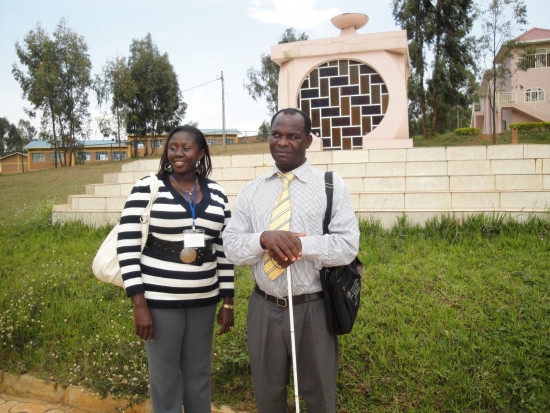 Felician Mkude (right) and Nancy Aswani Amwoso (left) stand in front of an outdoor monument to the genocide victims.
