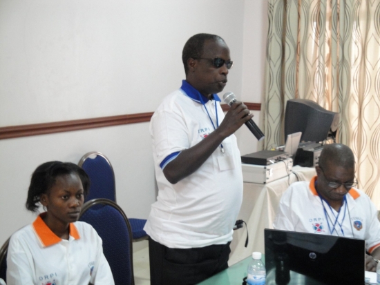 Kinubi Francis speaks into a microphone with other participants seated around him.