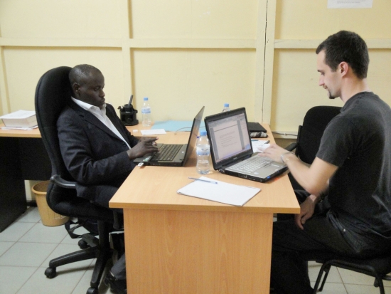 Oswald Tuyizere and Chris Lytle sit on opposite sides of a desk 