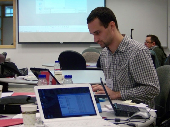 Chris Lytle is sitting a table crowded with laptops, water bottles and papers.