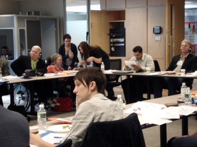 <p>
	Delegates are sitting around a conference table, participants face each other and listen to a presenter who is outside the frame.</p>
