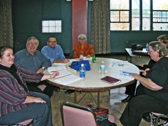 Participants smile while seated around a table littered with training materials and plastic bottles.