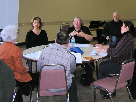 <p>
	Training participants are seated and conversing around a circular table.</p>
