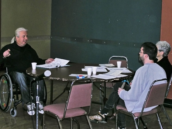 <p>
	Normand Boucher speaks with Lyne Robichaud and Jean-Michel Bernier as they sit around a table littered with training materials and styrofoam cups.</p>
