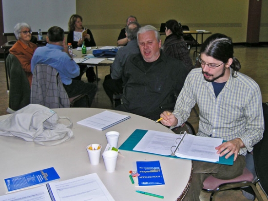 Normand Boucher and Francis Charrier are at a table working with the training materials.