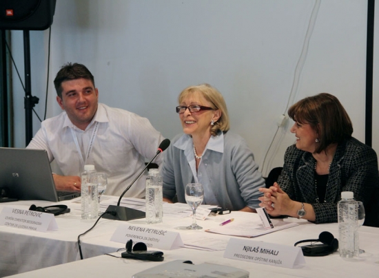 Nevena Petrušić and Radovan Radulović smile while looking at Vesna Petrović who is speaking into a microphone and smiling broadly.