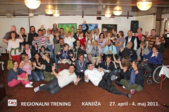 Participants stand and sit close together and smile for a group photo in the training room.