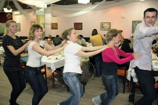 <p>
	Five participants hold on to one another and dance in single file.</p>
