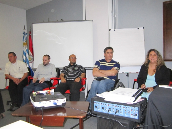 Jose Leal, Germán Sciurano, Guillermo Pinilla, Ronaldo Bacry and Carolina Buceta, Carolina speaks into the microphone. All participants are seated and there are flip charts behind them. 