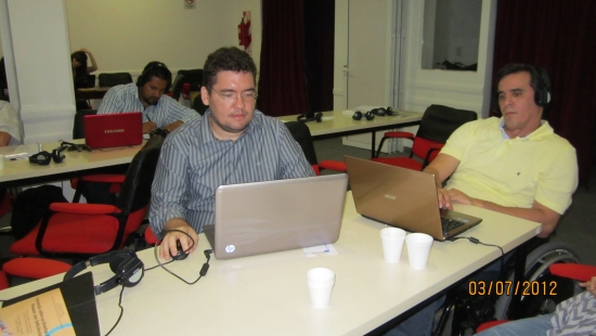 Ronaldo Bacry and Alexandre Mapurunga are seated at a table and are looking at their computers. 