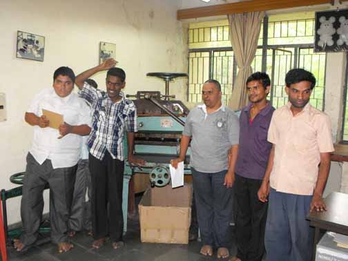 <p>Male trainees at the National Institute for the Mentally Handicapped pose on either side of a printing press</p>
