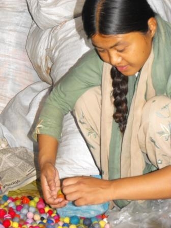 <p>Woman from Entire Power in Social Action crouching down working on crafts</p>
