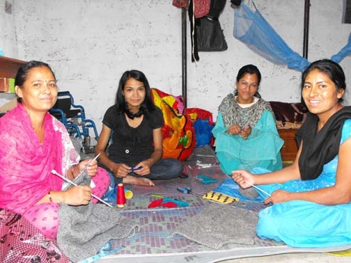 <p>Four women from Entire Power in Social Action sitting in a semi circle on the ground working on crafts and smiling</p>
