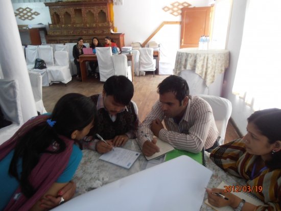 <p>
	Four participants gather around a table and work together on an training exercise.</p>
