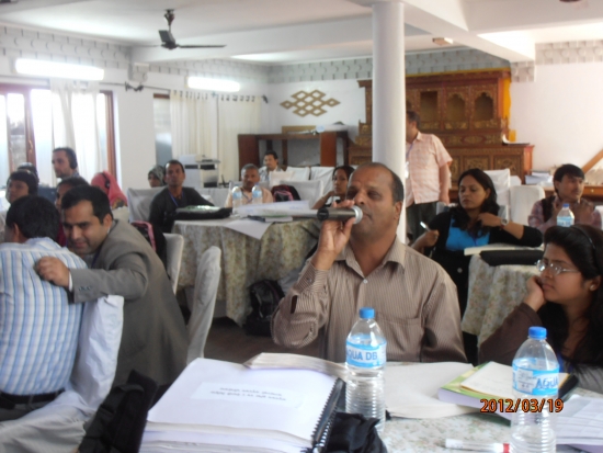 <p>
	Seated, a participant makes a comment in the microphone surrounded by the other participants.</p>
