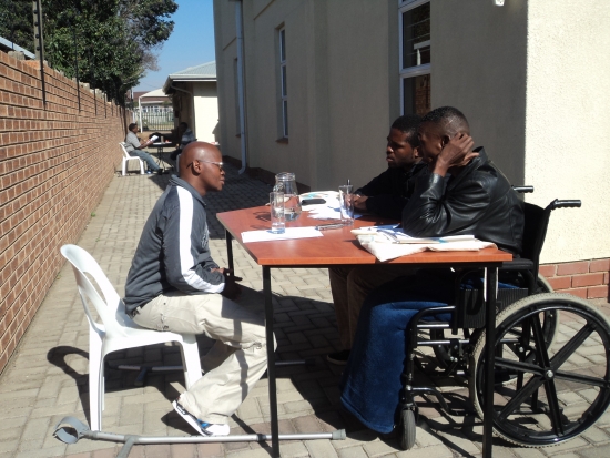 Lubabalo Mbeki is siting in front of Muntezihlupha Sibiya Wiseman and Sibusiso Sithole at a table outside of the training venue.
