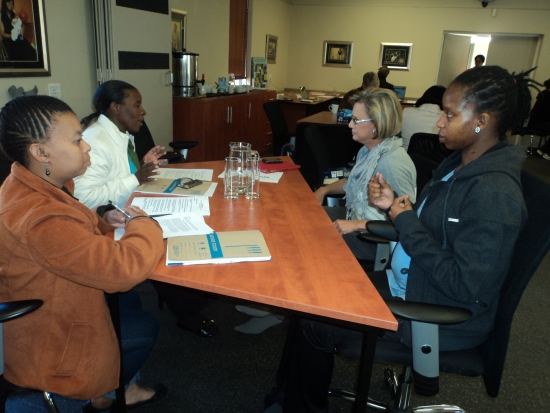 Vanessa dos Santos, Betty Masipa, Phumza Sikumba and Judith Madi  are sitting in the training room at a big table. 