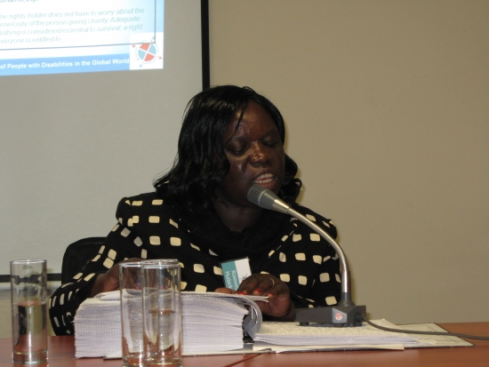 Roseweter Mudarikwa at the table with microphone, facilitating the session using brailled materials.