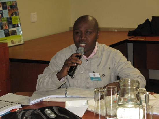 <p>
	Surprise Mokgope is sitting at a table with a microphone giving his comments during the session.</p>
