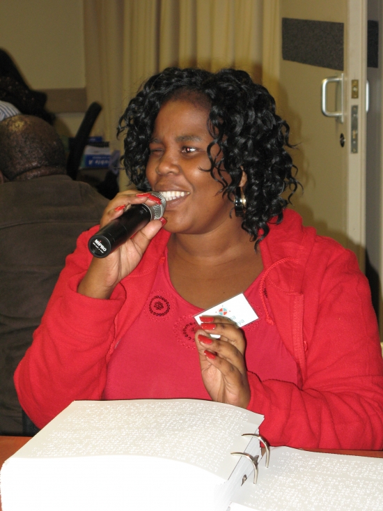 Zama Ngwenya holds a microphone at a table