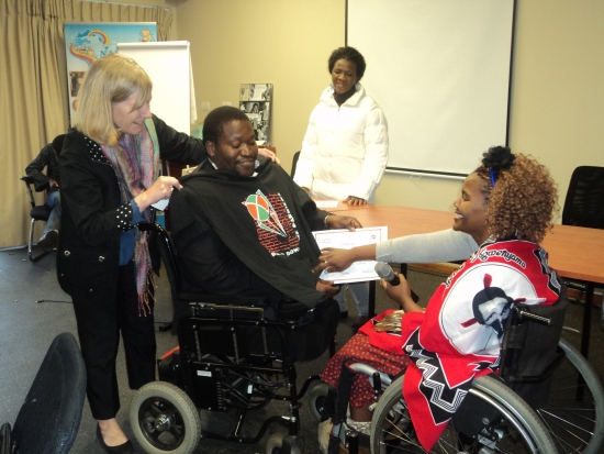 <p>
	Sipho Innocent Nkosi is being given a DRPI T-shirt from Marcia Rioux, while Bongiwe Malope is handing over the certificate. Someone looks on in the background.</p>
