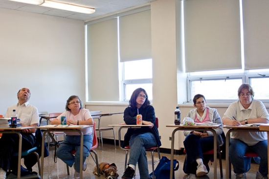 Monitors seated abreast in small desks during training.