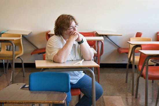 Mary Jo Power sitting at a desk and looking off toward a window toward the right. 