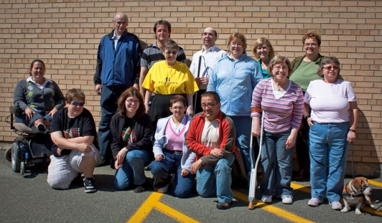 A outdoor group shot of the seminar participants, who are posed against a yellow brick wall.