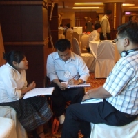 Mr. Chaiya, Ms. Phoutsadyand Mr. Khamphon sit together and work with training materials. 