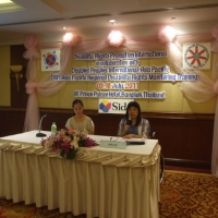 Ms. Saowalak Thongkuay sits at a table with Chona Sabo and speaks into a microphone. 