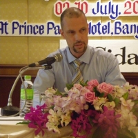 Mr. Patrik Andersson sits at a table and speaks into a microphone. 